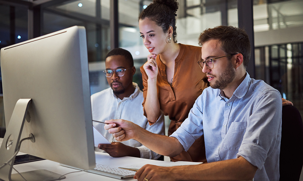 picture of workers gathered round a computer screen